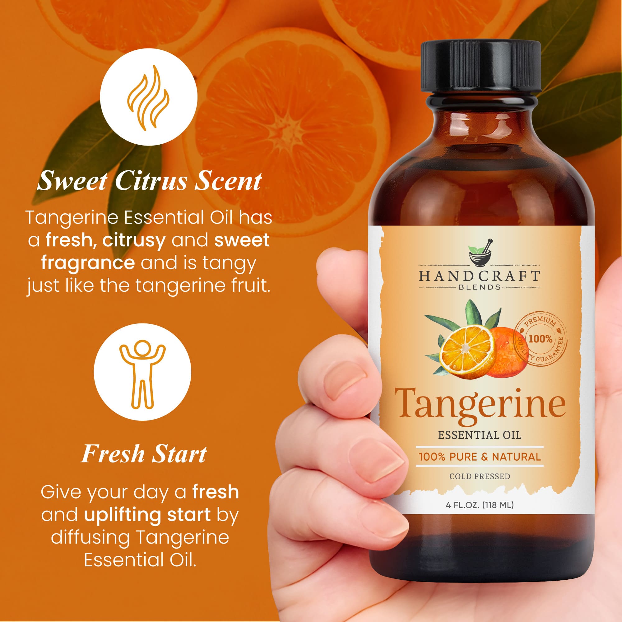 Hand holding a 4oz amber bottle of tangerine essential oil with sliced tangerines on orange background