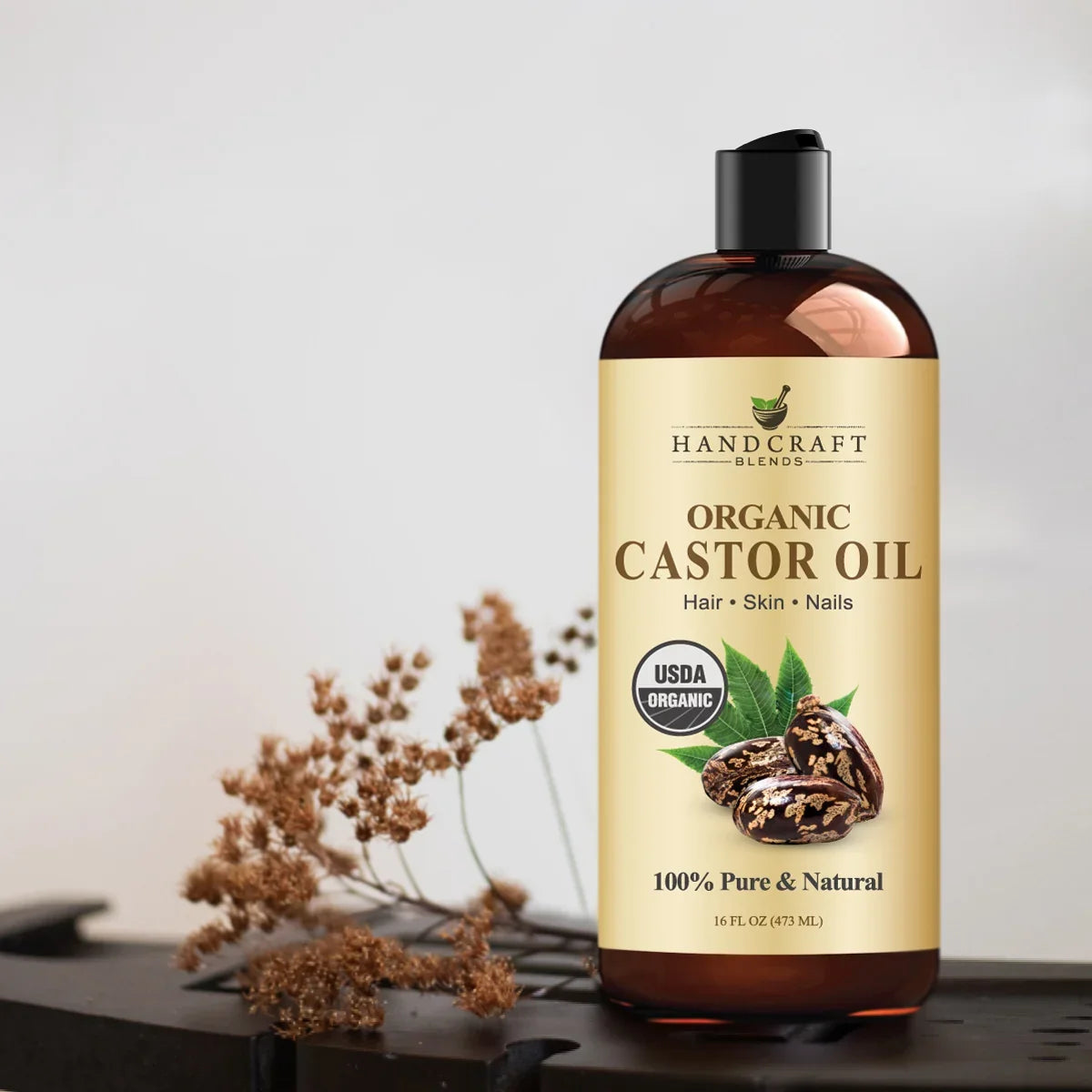 Bottle of organic castor oil for hair, skin, nails with dried flower accent.