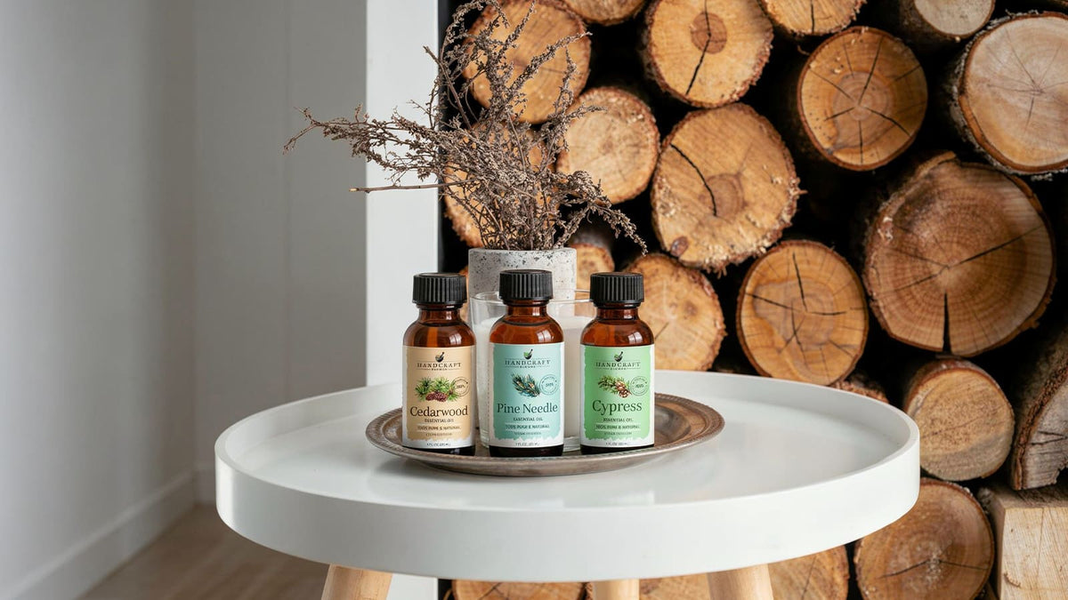 Woodsy candles in smoked glass jars with wooden wicks beside pine sprigs, cypress branches, and cedar shavings