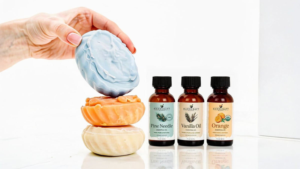 Pale handmade soap bars wrapped in white paper beside lemons, rosemary sprigs, and amber essential oil bottles