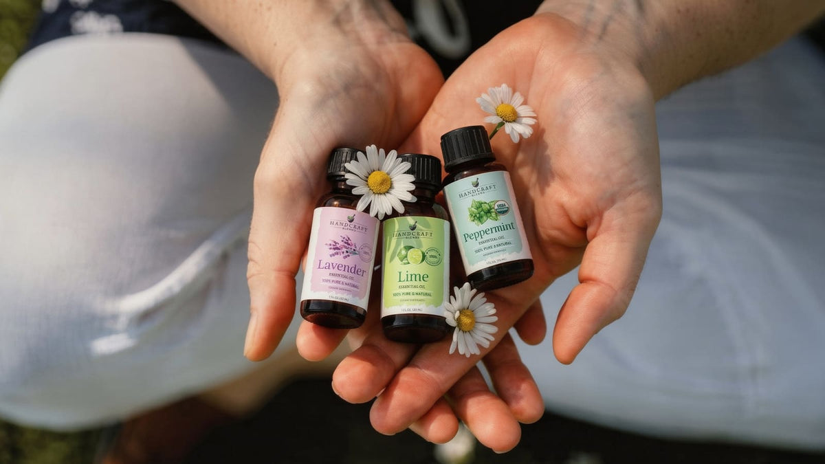 Lemon and rosemary essential oil bottles beside a clear carrier oil on a minimalist shelf