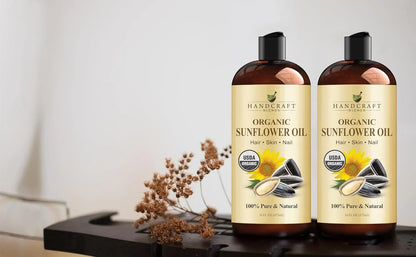 Two bottles of organic sunflower oil for hair, skin, and nails on a table with dried flowers.